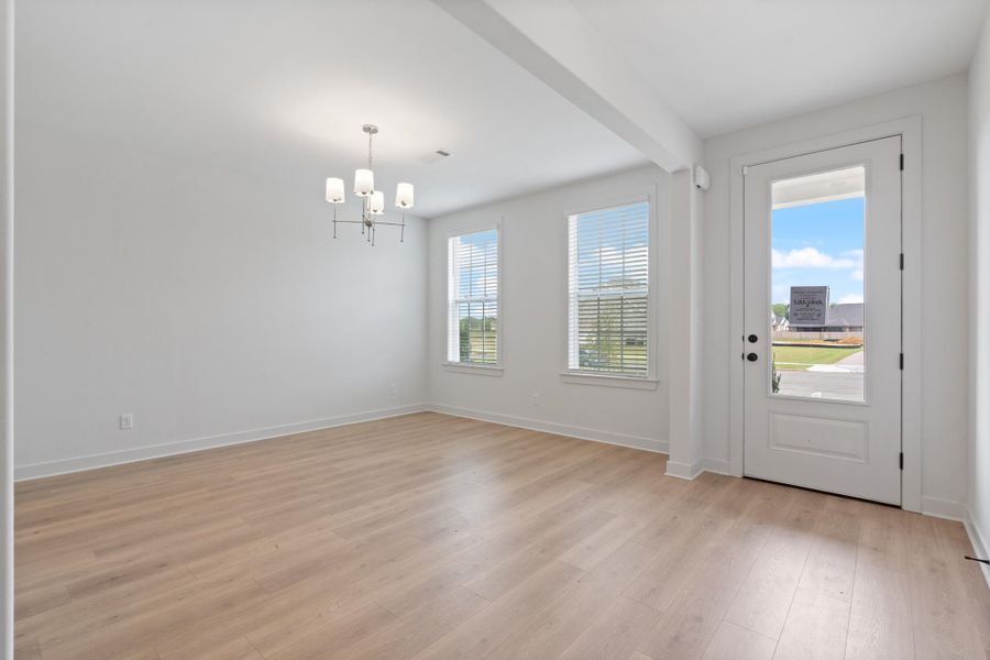 Wood-finish flooring, multiple windows with blinds, a modern chandelier, and a glass-paneled exterior door Wood-finish flooring, multiple windows with blinds, a modern chandelier, and a glass-paneled exterior door