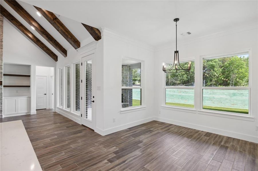 Unfurnished dining area with dark wood-type flooring, beamed ceiling, a notable chandelier, and built in shelves