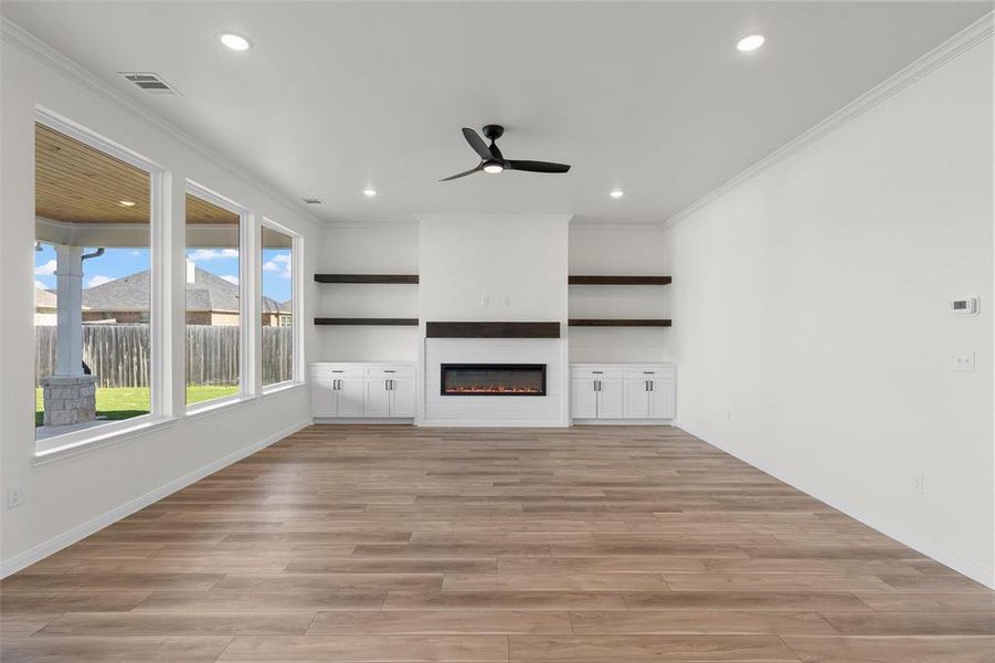 Unfurnished living room with ornamental molding, a glass covered fireplace, light wood finished floors, ceiling fan, and recessed lighting
