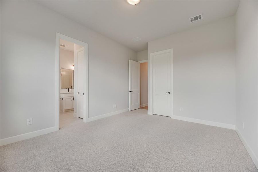 Unfurnished bedroom featuring light carpet and connected bathroom