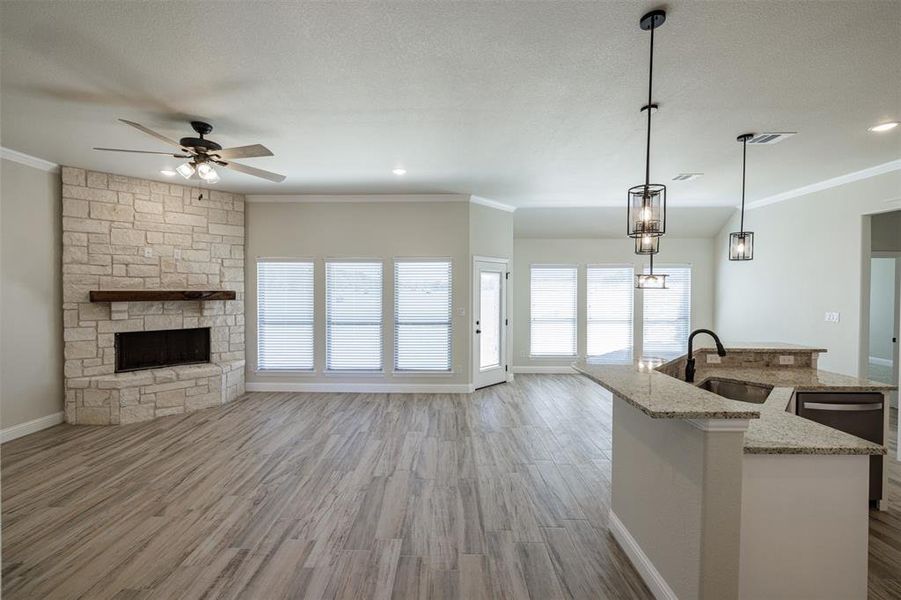 Kitchen featuring an island with sink, light stone countertops, light hardwood / wood-style flooring, sink, and decorative light fixtures