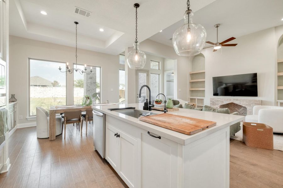 The kitchen, dining, and living areas come together beneath tall ceilings, with a wall of oversized windows keeping the backyard in view.