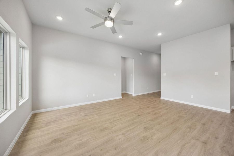 A spacious room offers light wood flooring, contemporary lighting, and ample natural light from generous windows.