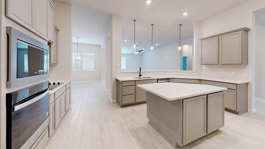 Kitchen with light countertops, gray cabinets, a kitchen island, and stainless steel appliances Kitchen with light countertops, gray cabinets, a kitchen island, and stainless steel appliances