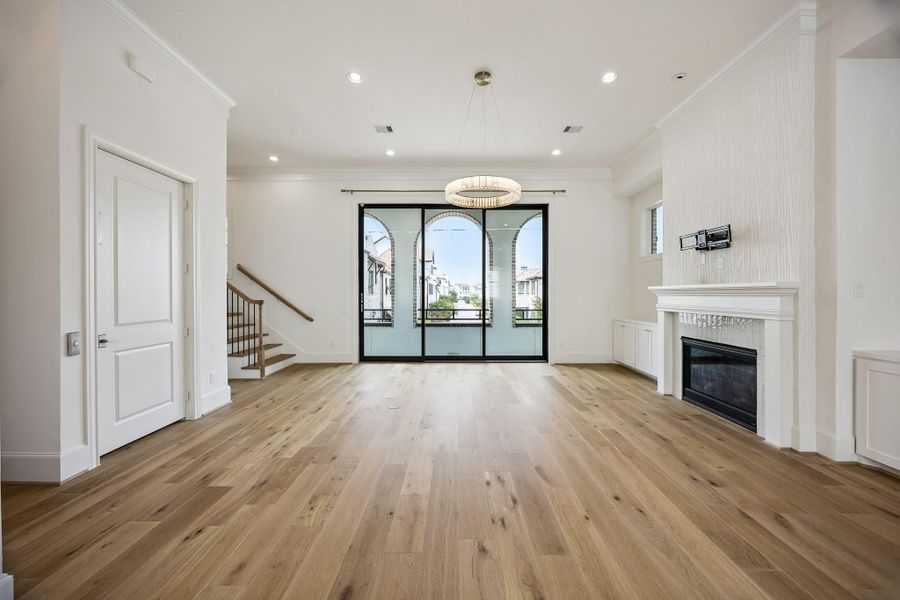 Expansive second-floor living area with hardwood floors, fireplace and 12-foot ceilings.  The wallpapered mantel and designer light fixture add a distinctive, sophisticated touch.  Let's to through the sliding 10' glass panels.