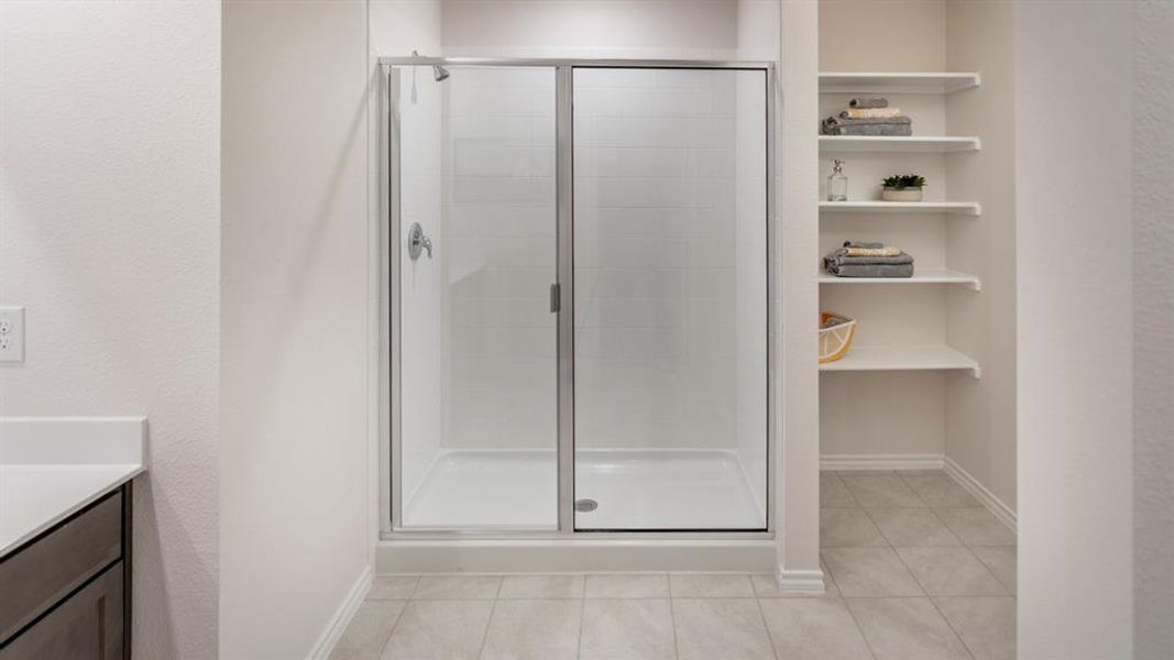 Full bath featuring a stall shower, vanity, a textured wall, and light tile patterned flooring