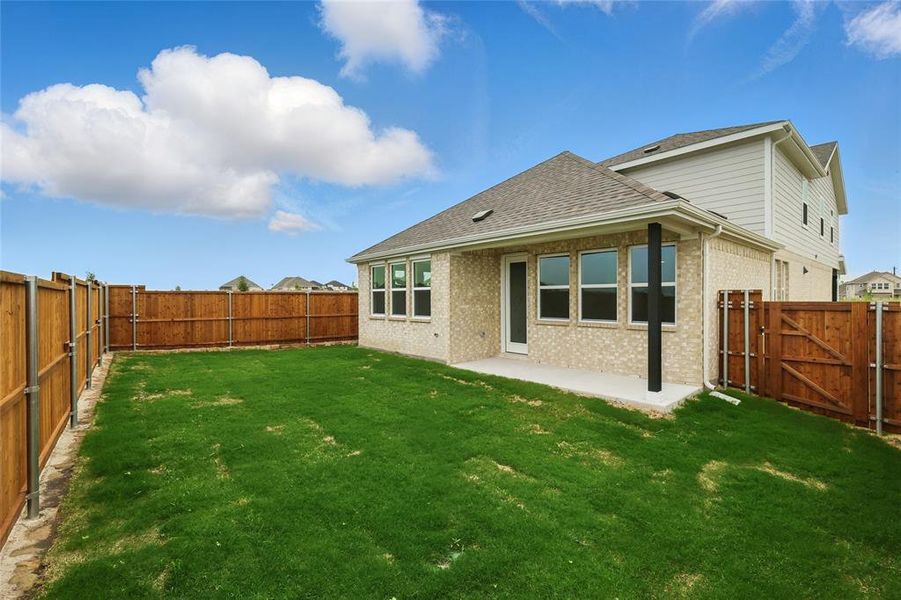 Back of property with a fenced backyard, a shingled roof, brick siding, and a patio area Back of property with a fenced backyard, a shingled roof, brick siding, and a patio area