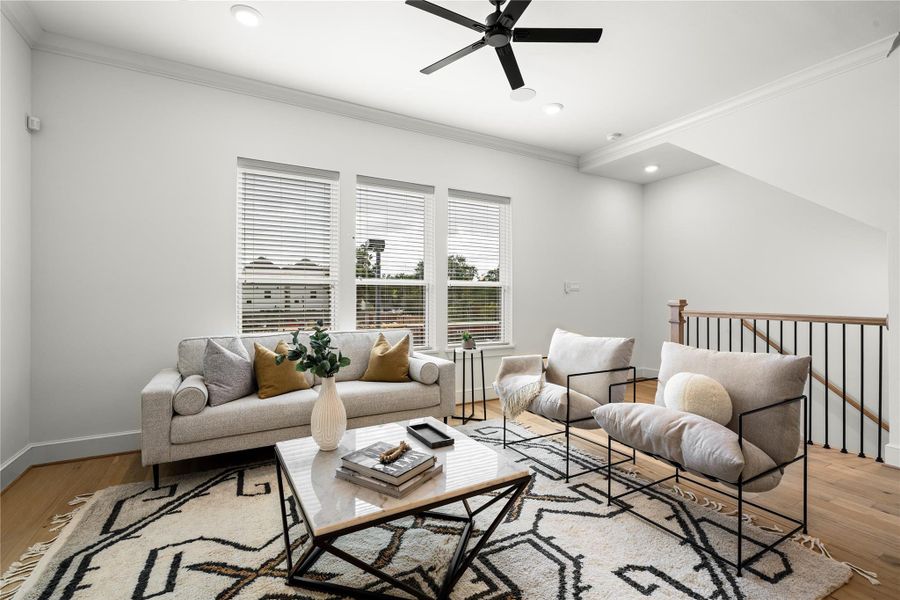 Stairs from the first floor lead into this bright and inviting living room featuring large windows, hardwood floors, and recessed lighting - perfect for relaxing or entertaining.