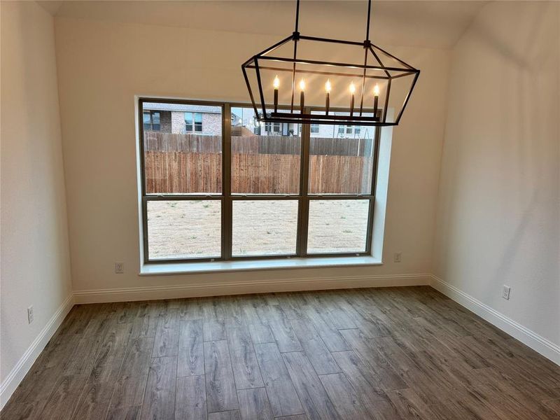 Unfurnished dining area featuring an inviting chandelier, plenty of natural light, and wood-type flooring