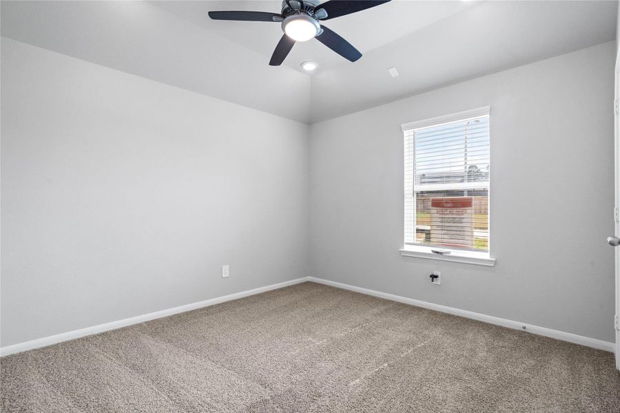 This cozy secondary bedroom offers plush soft carpeting, neutral walls ready for personalization, a sun-filled window with fitted blinds, sloped ceilings with ceiling fan, and a spacious closet for all your storage needs.