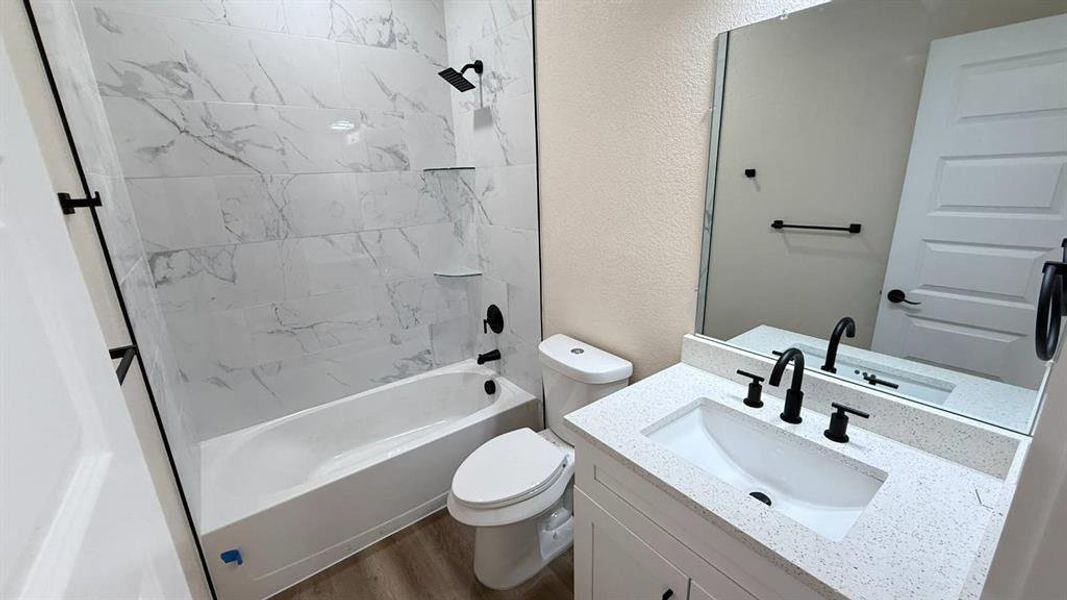 Full bath featuring a textured wall, shower / bathtub combination, vanity, and dark wood-style floors