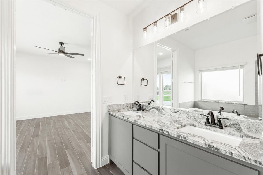 Bathroom with double vanity, gray cabinets, granite countertops, and large mirror with overhead lighting Bathroom with double vanity, gray cabinets, granite countertops, and large mirror with overhead lighting