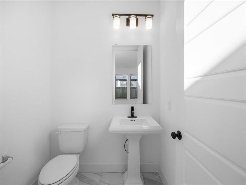 Half bathroom featuring marble finish floors and toilet Half bathroom featuring marble finish floors and toilet