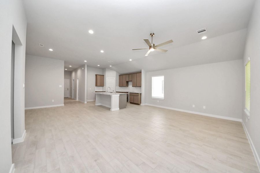 Family room flooded with natural light through the expansive windows.  The premium tile flooring adds a touch of luxury to the space, creating the perfect setting for relaxing moments and cherished gatherings with loved ones. Sample photo of completed home with similar floor plan. Actual colors and selections may vary.