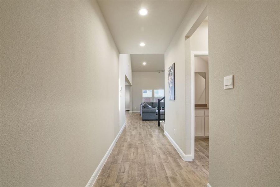 Hallway with a textured wall, light wood finished floors, and recessed lighting Hallway with a textured wall, light wood finished floors, and recessed lighting