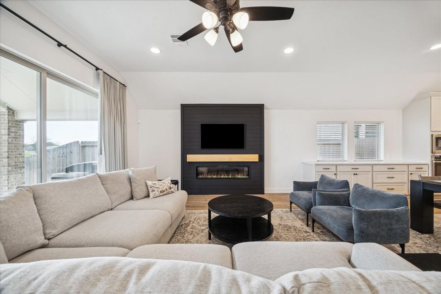 The living room showcases a gorgeous custom electric fireplace wall.