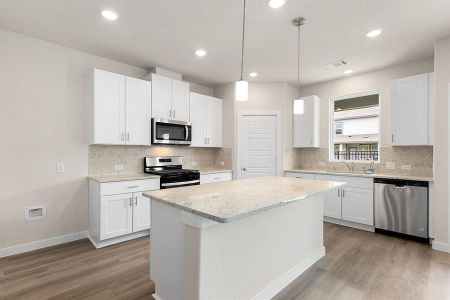 This stunning kitchen displays such a beautiful  ambience with the cotton white cabinets, neutral paint, granite countertops, light modern backsplash, and SS appliances, oversized kitchen island with extra storage, breakfast bar, recessed lighting, high ceilings and pantry.