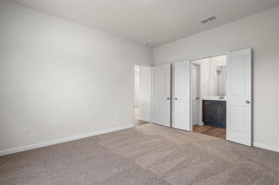 Unfurnished bedroom with dark colored carpet and connected bathroom