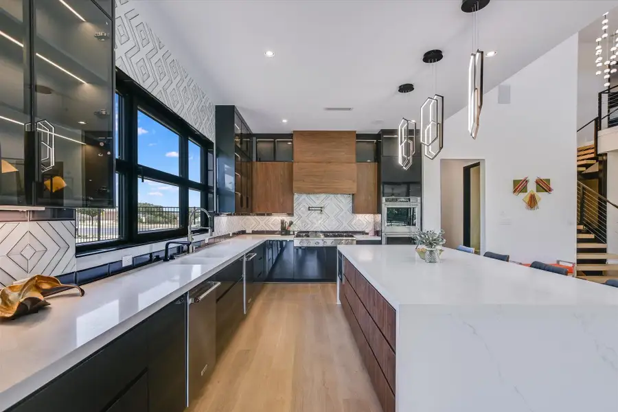 Kitchen featuring modern cabinetry, tasteful tile backsplash, light wood flooring, stainless steel appliances, and glass insert cabinets Kitchen featuring modern cabinetry, tasteful tile backsplash, light wood flooring, stainless steel appliances, and glass insert cabinets