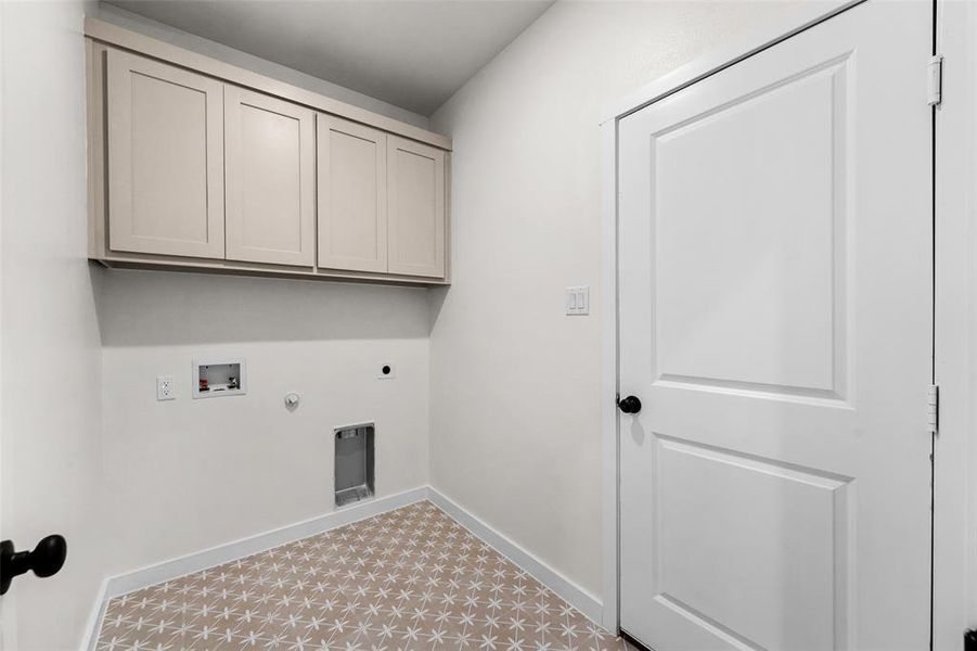 Utility space featuring neutral wall paint, patterned floor tile, and upper cabinetry Utility space featuring neutral wall paint, patterned floor tile, and upper cabinetry