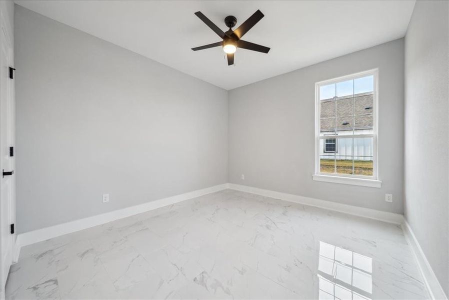 Empty room featuring ceiling fan and a wealth of natural light