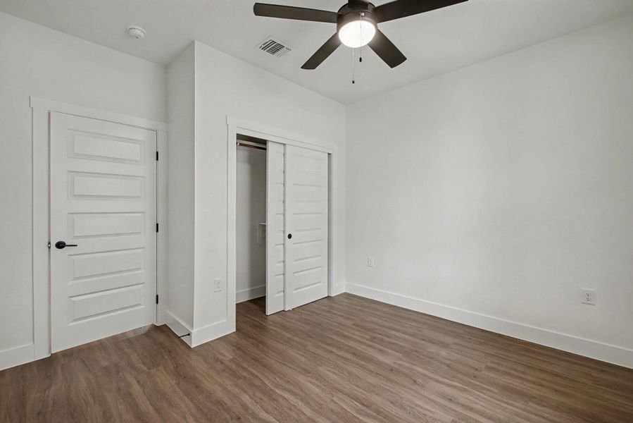 Unfurnished bedroom featuring dark wood finished floors, a closet, and a ceiling fan