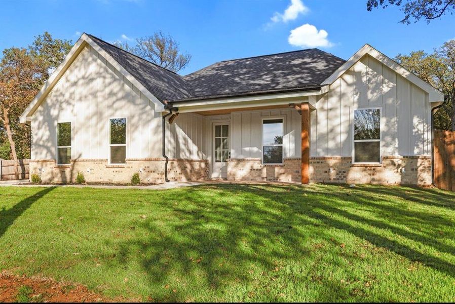 View of front of property featuring brick siding, a porch, roof with shingles, and board and batten siding