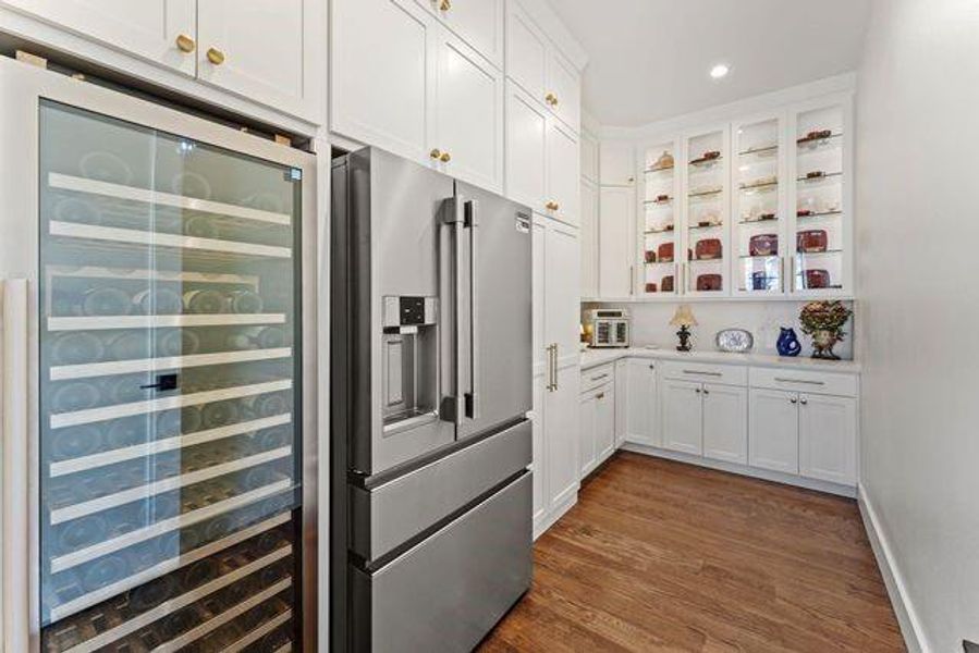 Pantry featuring Beverage cooler, high quality fridge, white cabinetry, light countertops, and glass insert cabinets
