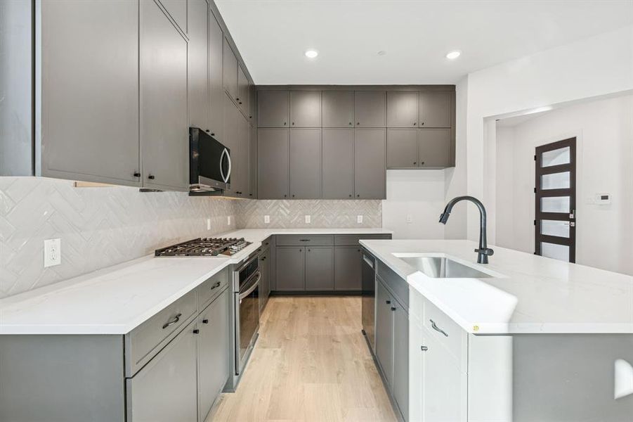 Quartz countertops, gas burner cooktop and black accent hardware.
