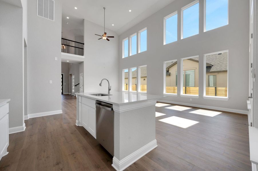 Kitchen featuring dark wood-type flooring, open floor plan, dishwasher, white cabinetry, and a towering ceiling