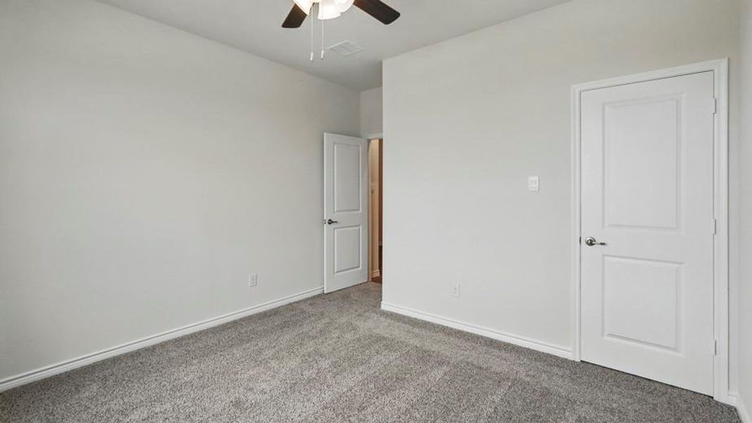 Carpeted room featuring light gray walls, white baseboards, and a ceiling fan with a dark wood-finish motor