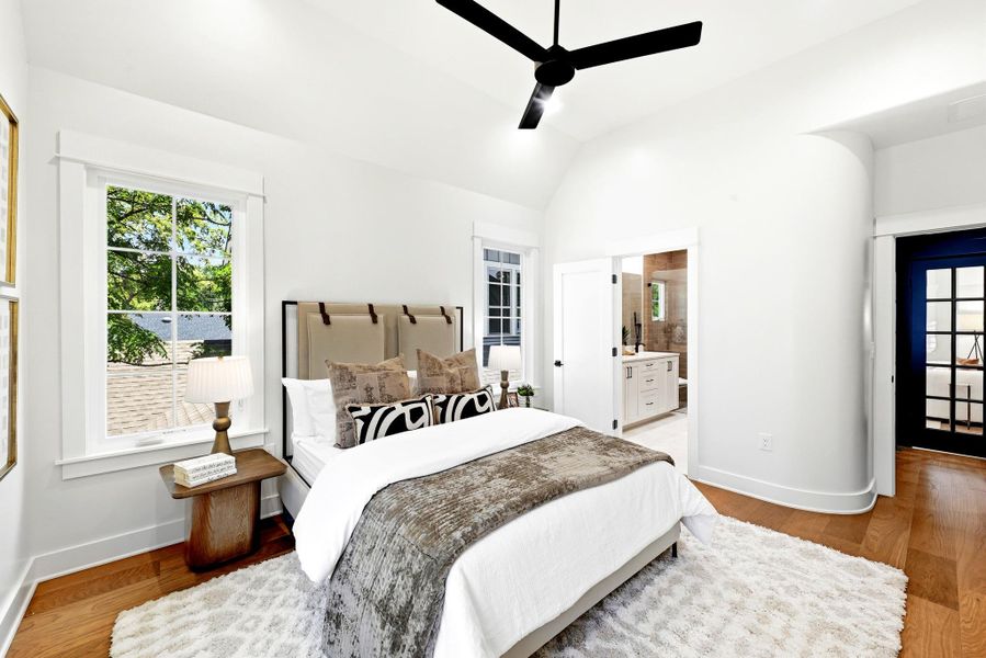A well-lit bedroom with high ceilings and warm wood flooring. A well-lit bedroom with high ceilings and warm wood flooring.