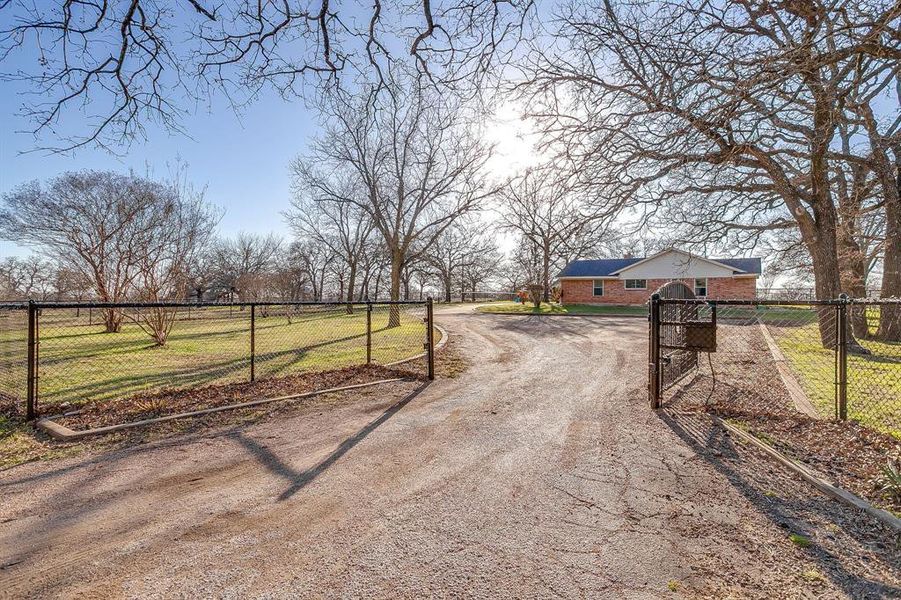 View of road with a gate, a gated entry, and a rural view