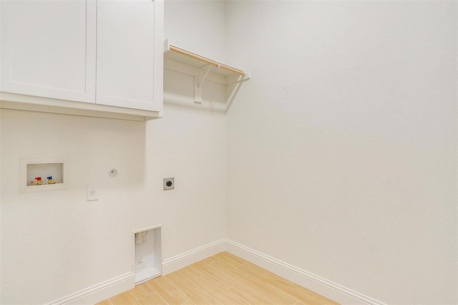 Laundry area featuring washer hookup, hookup for a gas dryer, cabinets, light hardwood / wood-style floors, and electric dryer hookup