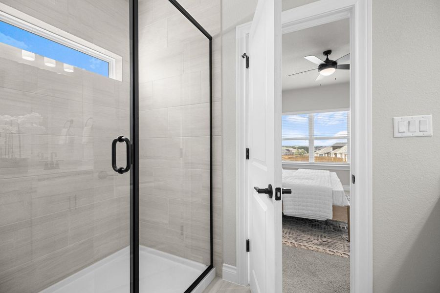 Full bath featuring connected bathroom, a shower stall, light colored carpet, and ceiling fan
