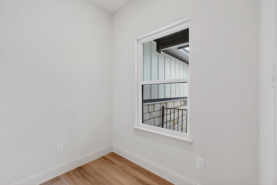 Interior room with white walls, wood-finish flooring, and white baseboards Interior room with white walls, wood-finish flooring, and white baseboards