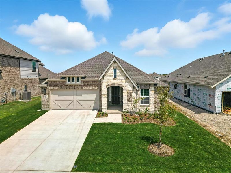 View of front facade featuring a shingled roof, stone siding, driveway, a front yard, and a garage View of front facade featuring a shingled roof, stone siding, driveway, a front yard, and a garage