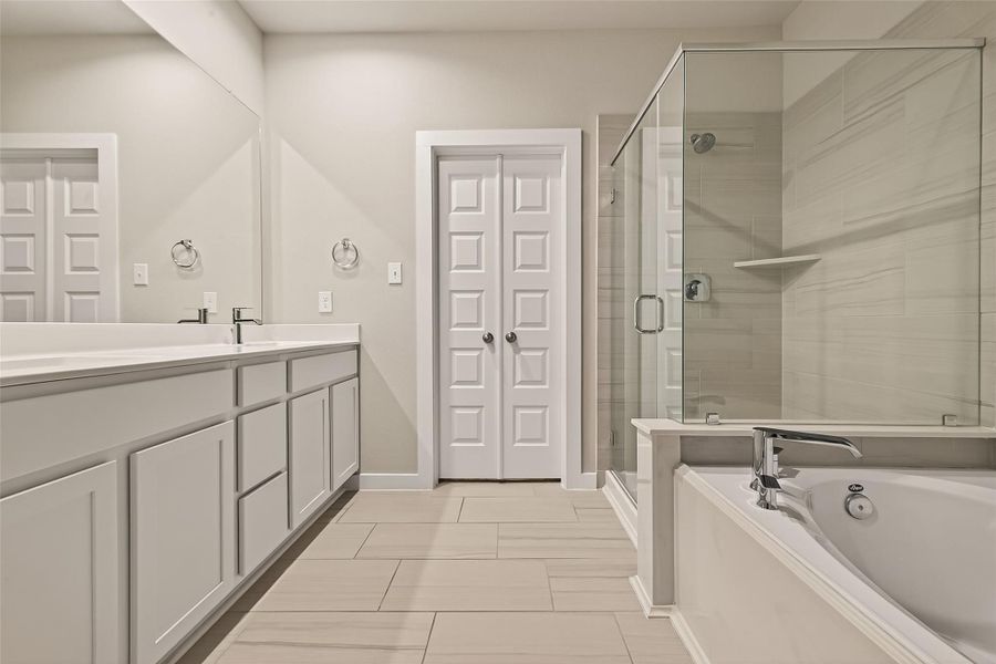A closer view of the primary bathroom shows the layout, including the shower, jetted tub, double sinks, and storage areas.