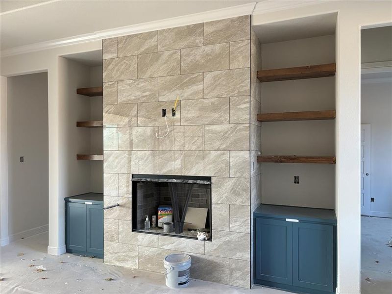 Unfurnished living room with crown molding, built in features, and a fireplace