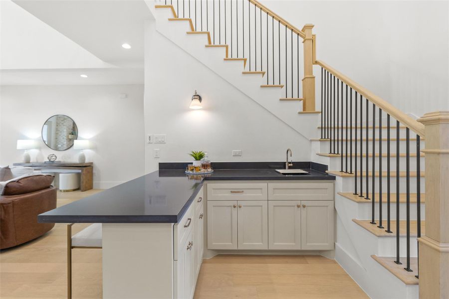 This tucked-in wet bar adds a smart layer of functionality right where you need it. Positioned beneath the staircase, it’s perfect for serving drinks, setting up a coffee station, or hosting without running back to the kitchen. The contrast countertop and integrated sink make it feel intentional and elevated—an everyday convenience that quietly upgrades how you entertain.