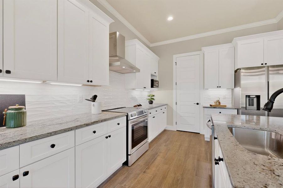 Bright kitchen featuring white shaker cabinetry, stainless steel appliances, granite countertops, and wood-finish flooring