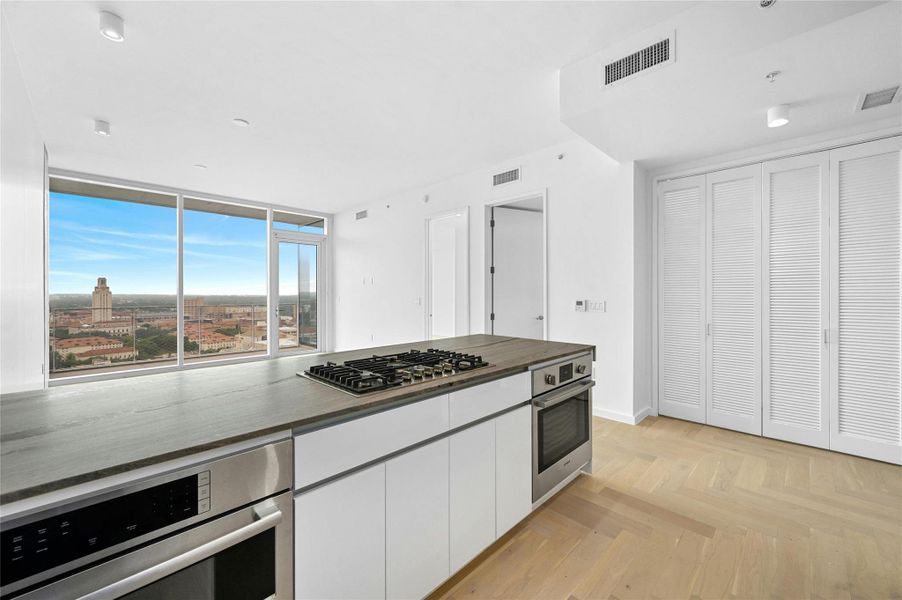 Residence 1702 offers an open living design with a chef-inspired kitchen featuring Bosch® appliances, gas cooktop, and a stone waterfall island. Floor-to-ceiling windows open to a private balcony and capture stunning views of the UT Tower and Austin skyline.