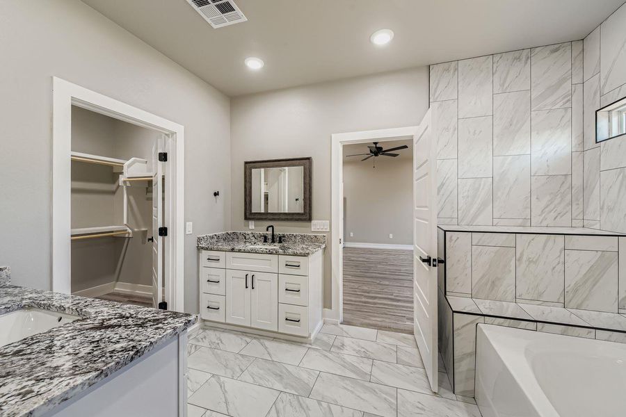 Full bath with two vanities, a garden tub, light marble finish flooring, a ceiling fan, and recessed lighting
