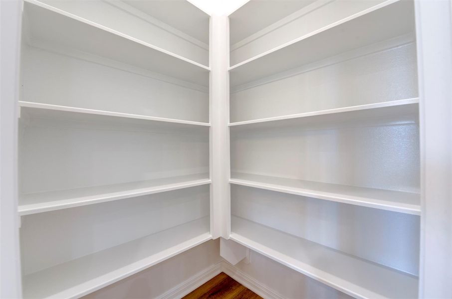 Spacious walk-in pantry with built-in shelving, offering ample storage and easy organization for everyday living.