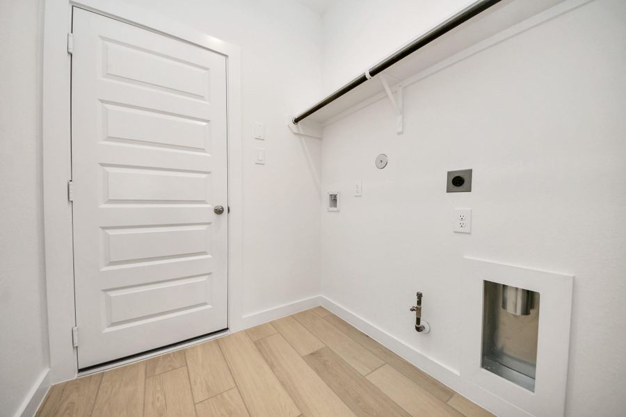 A perfect blend of functionality and comfort. Capture the essence of easy living with a first-floor laundry room, thoughtfully equipped with shelving for effortless organization. Both electric and gas connections available. Sample photo of completed home with similar floor plan. Actual colors and selections may vary.