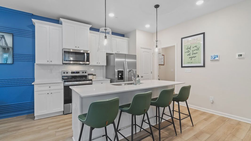 Modern kitchen with large island, pendant lighting, and open layout in new townhome at Auburn Ridge in Riverdale, GA.