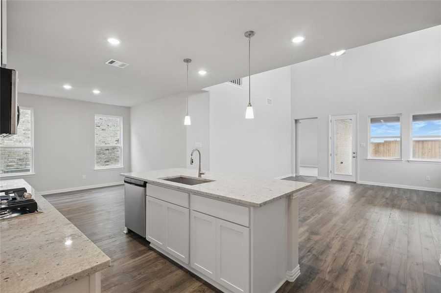 Kitchen featuring light stone counters, open floor plan, healthy amount of natural light, a kitchen island with sink, and recessed lighting