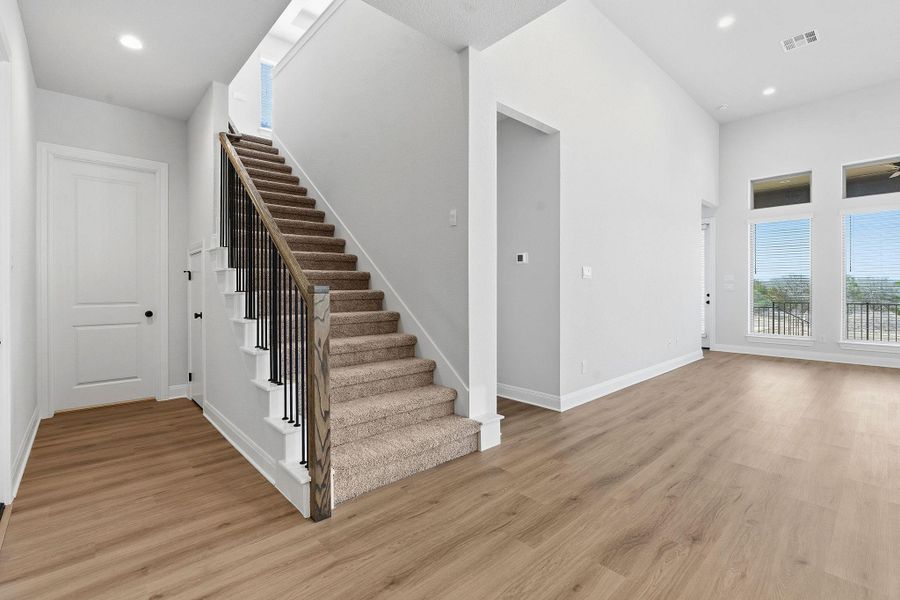 Stairway with recessed lighting, wood finished floors, and a high ceiling
