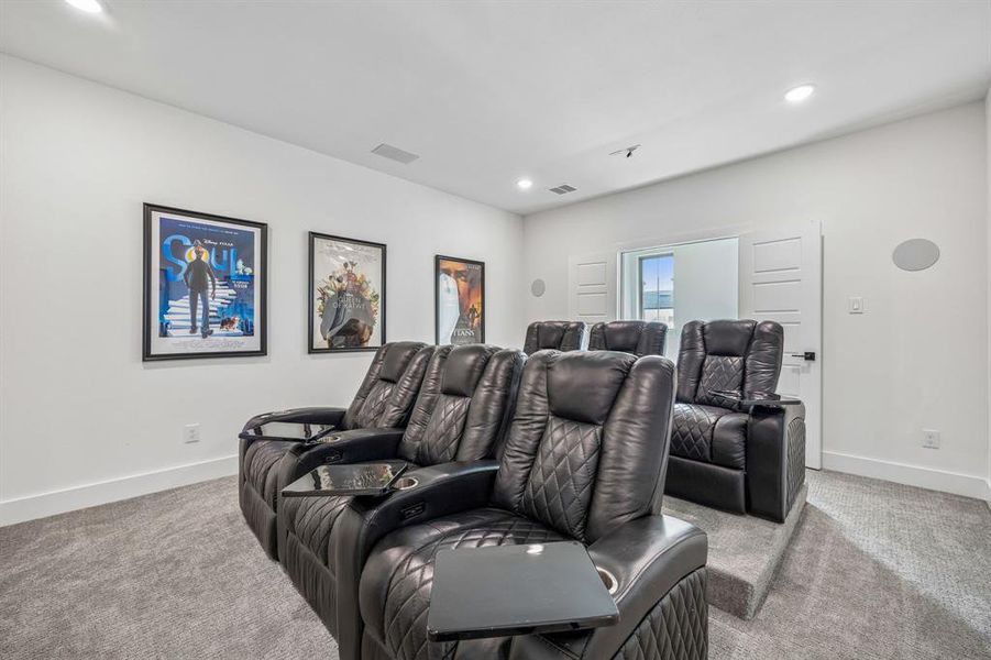 Home theater room with light colored carpet and recessed lighting