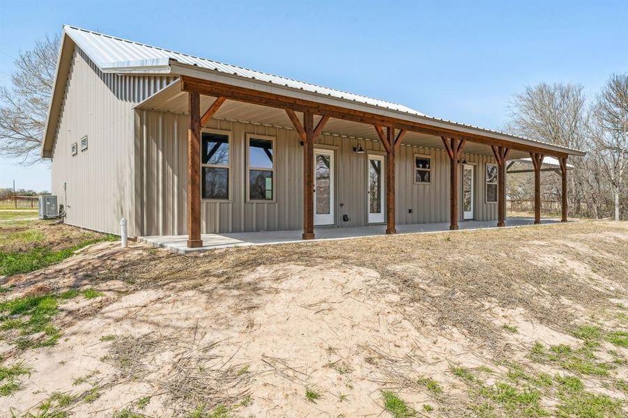 Back of property with covered porch, central AC unit, and metal roof